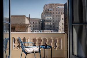 uma varanda com 2 cadeiras e vista para a cidade em grey l studio apartments Downtown Cairo Bidair House em Cairo