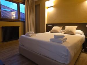 a bedroom with a large white bed with towels on it at Hotel Santa Catalina by Bossh Hotels! in A Coruña