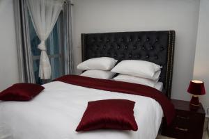 a bedroom with a large bed with red and white pillows at Martha House New BELL Douala in Douala