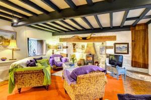 sala de estar con muebles de color púrpura y chimenea en Ty Uchaf, en Dolbenmaen