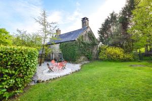 una casa con dos sillas y una mesa en un patio en Ty Uchaf, en Dolbenmaen