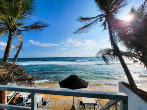 Blick auf den Strand mit Palmen und das Meer in der Unterkunft Beach Cabana By why not hikkaduwa in Hikkaduwa