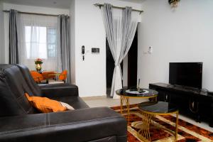a living room with a black couch and a television at Martha House New BELL Douala in Douala
