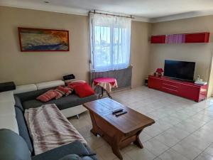 a living room with a couch and a tv at Pavillon du Capitaine -25min Parc-By R&G in Montournais