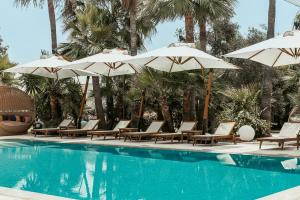 una piscina con sedie, ombrelloni e alberi di Averde Residence a Larnaka