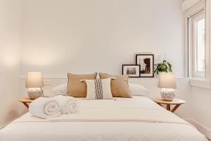 a white bedroom with a large white bed with two lamps at Main Street Deluxe in A Coruña