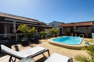 a patio with a swimming pool and a house at Village Itaúna Inn - Casas de Temporada in Saquarema