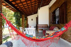 a red hammock on a patio with a table and chairs at Village Itaúna Inn - Casas de Temporada in Saquarema