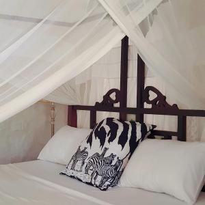 Una cama con una almohada blanca y negra. en C House, en Malindi