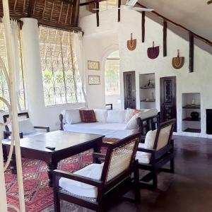 una sala de estar con un sofá, una mesa y sillas en C House, en Malindi