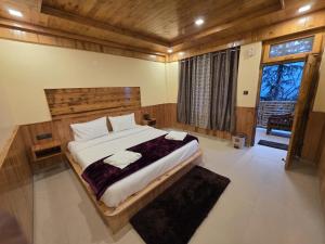 本贾尔Sojha Hills Hotel & Restaurant的一间卧室，配有一张大床和一扇大窗户。