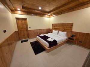 本贾尔Sojha Hills Hotel & Restaurant的卧室里有一张大床，配有木质天花板