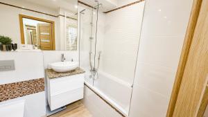 a white bathroom with a shower and a sink at Apartament Ptasia Góra in Kłodzko