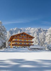 uma cabana de madeira nas montanhas com um campo coberto de neve em Hotel Rösslhof em Ramsau am Dachstein