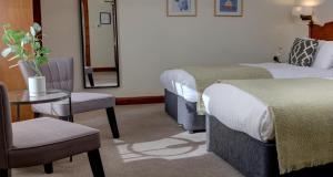 a hotel room with two beds and a table and chairs at BEST WESTERN The Crianlarich Hotel in Crianlarich