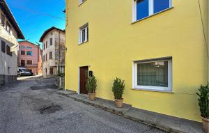 a yellow building with potted plants on a street at Nice Home In Longarone With Wifi in Faè +11 photos