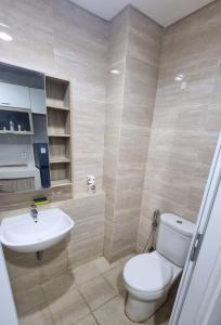 a bathroom with a white toilet and a sink at Apartemen Springwood by tuliproom in Pakulonan Dua +15 photos