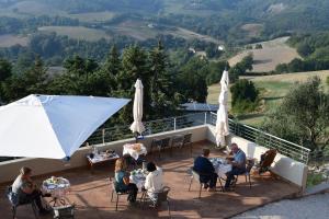 um grupo de pessoas sentadas em mesas num convés em Green B&B Urbino Cá del vento em Urbino