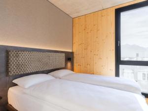 a bedroom with two white beds and a window at B&B HOTEL Liechtenstein-Eschen in Eschen