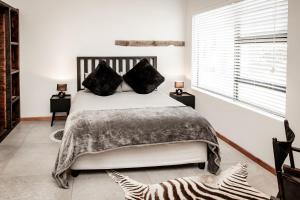 une chambre avec un grand lit blanc avec des oreillers noirs dans l'établissement Zoetvlei Dairy House, à Paterson 12 autres photos