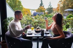 a man and a woman sitting at a table drinking coffee at Wellness & SPA boutique Hotel pod lipkami Prague in Prague