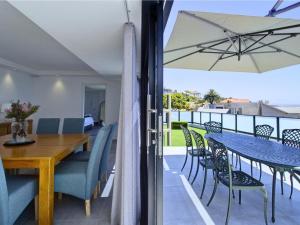 a dining room and balcony with a table and chairs at Mossel-Bay Waterfront Accommodation in Linkside