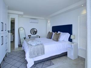 a white bedroom with a large bed and a mirror at Mossel-Bay Waterfront Accommodation in Linkside