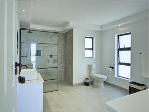 a bathroom with a toilet and a glass shower at Mossel-Bay Waterfront Accommodation in Linkside +78 photos