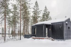 un edificio nero nella neve con gli alberi di Tyven Resort a Sirkkakoski