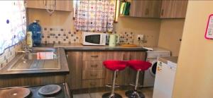a kitchen with two red stools in front of a sink at Waterworks Overnights in Kimberley