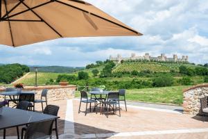 un patio con tavoli e sedie con un castello sullo sfondo di Borgo Campassini, Monteriggioni a Monteriggioni