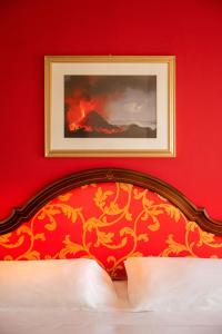 a bedroom with a red wall with a picture above a bed at Hotel Isabella in Taormina