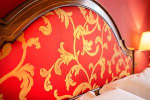 a bedroom with a red wall with a gold patterned headboard at Hotel Isabella in Taormina