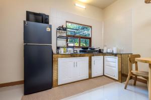 eine Küche mit einem schwarzen Kühlschrank und einem Tisch in der Unterkunft Villa Casa Blanca in Ban Madua Wan