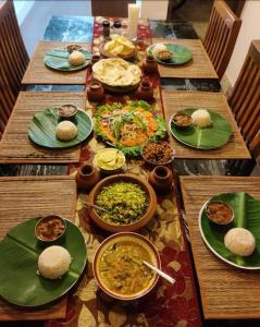 einen langen Holztisch mit Teller Essen drauf in der Unterkunft The Boho Stays Kochi in Kochi + 51 Fotos
