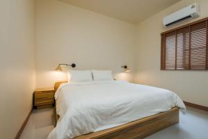 ein weißes Schlafzimmer mit einem weißen Bett und einem Fenster in der Unterkunft Villa Casa Blanca in Ban Madua Wan