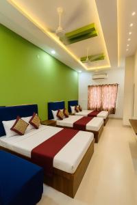 a row of beds in a room with green walls at Hotel Tirupati Residency Ujjain # Near Mahakal Mandir And Railway Station # Top rated in Ujjain +5 photos