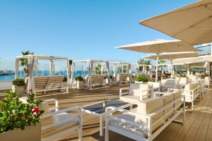 Una fila de sillas blancas y sombrillas en una terraza. en AluaSoul Palma Hotel Adults Only, en Can Pastilla