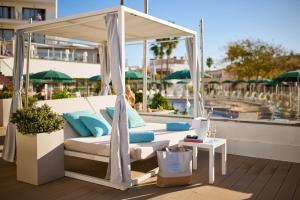 una cama con dosel en una terraza junto a una piscina en AluaSoul Palma Hotel Adults Only, en Can Pastilla