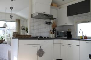 una cucina con mobili bianchi e un forno a microonde di Weideveld 60 Michelle a Den Burg Altre 4 foto