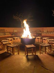 a large fire pit with benches and tables in front of it at DesertGlow camp in Merzouga