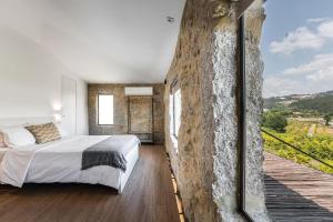 a bedroom with a bed and a stone wall at Romantic Lemon Grove Cottage with Private Pool - Oporto Lemon Farm, near Porto in Valpedre