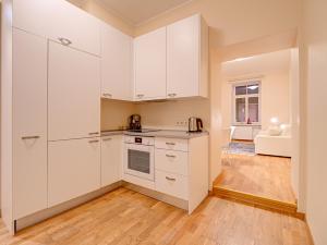 eine Küche mit weißen Schränken und ein Wohnzimmer in der Unterkunft Old Town Doma View 1BR Stays in Riga
