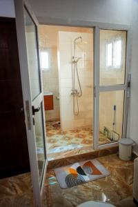 Un baño en remodelación con ducha y puerta de vidrio. en InfiniStay, en Abiyán