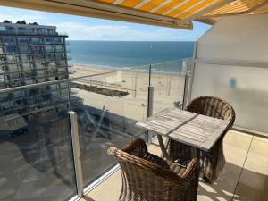 a table and chairs on a balcony with a view of the beach at Residence Wembley with sea view in Middelkerke