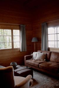 Una sala de estar con un sofá y dos ventanas. en For-Rest Lodge, en Broekhuizen