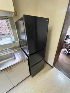 een zwarte koelkast in een keuken met een raam bij 青山ハウス in Otaru
