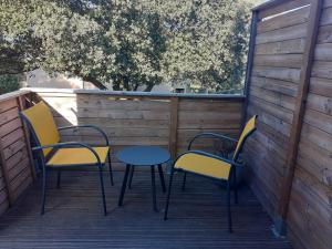 贝尔格新城Chambres d'hôtes Des couleurs et des Mots的甲板上的三把椅子和一张桌子