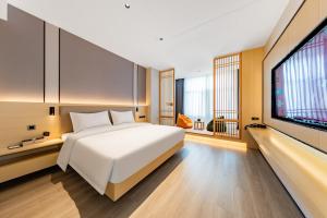 a bedroom with a white bed and a flat screen tv at Jin Yi X Hotel in Hekou