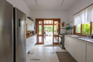 巴拉尤娜Casa Alto Padrao com 5 Suites e Jacuzzi Privativa的厨房配有白色橱柜和通往庭院的门